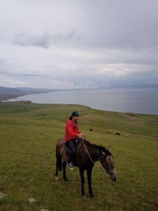 a woman riding a horse in a field at Song Kol lake, Flex Travel yurt camp, horse riding in Song-Kul