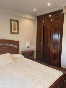 a bedroom with a bed and a wooden cabinet at PRIMERA LINEA PLAYA AMERICA in Nigrán