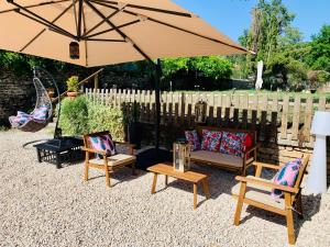 eine Terrasse mit Stühlen, einem Sonnenschirm und einer Schaukel in der Unterkunft Hôtel du Roy in Aisey-sur-Seine