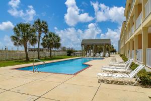 a swimming pool with lounge chairs and a gazebo at Dauphin Island Beach Club 210A in Dauphin Island