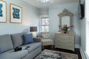 a living room with a couch and a dresser with a mirror at The Carroll Villa Hotel in Cape May