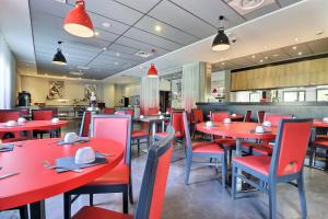 une salle à manger avec des tables et des chaises rouges dans l'établissement Hôtel des Lumières Lyon Meyzieu Arena Stadium, à Meyzieu