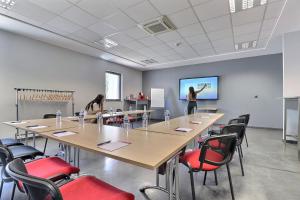 une salle de réunion avec une grande table et des chaises dans l'établissement Hôtel des Lumières Lyon Meyzieu Arena Stadium, à Meyzieu