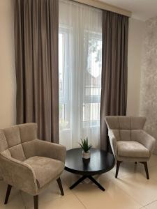 ein Wohnzimmer mit 2 Stühlen, einem Tisch und einem Fenster in der Unterkunft ĆAKA Luxury Rooms & Restaurant in Ćuprija