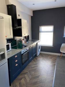 a kitchen with blue cabinets and a white appliance at Apartments on Albert Road with free parking in Blackpool