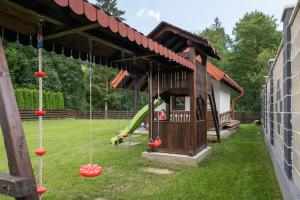 a playground with a play house and swings at Pensiunea Sofy Mar in Poiana Micului