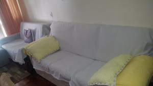 Un sofá blanco con dos almohadas junto a una ventana. en Apartamento Lindo e Aconchegante "com ou sem ar condicionado", en Porto Alegre