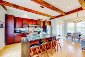 a kitchen with wooden cabinets and a large island with bar stools at Waterbury-Stowe Farmhouse Units 1-3 in Waterbury