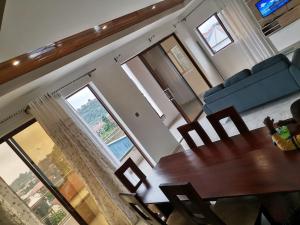 a living room with a table and chairs and windows at Studio de luxe chez FOUR IN ONE Résidence in Limbe