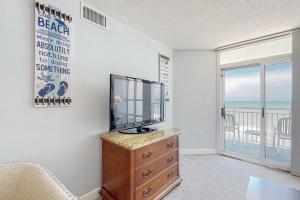 a living room with a tv on a dresser and a balcony at Carolinian Beach Resort 0730 in Myrtle Beach
