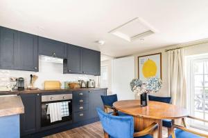 a kitchen with a wooden table and blue chairs at Cotswolds Cottage 5min from Soho Farmhouse in Chipping Norton