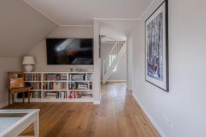 uma sala de estar com televisão e uma estante de livros em Aggas Hues em Oldsum