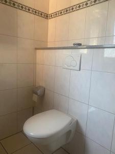 een badkamer met een wit toilet in een betegelde kamer bij In der Heide in Löhne