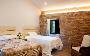 a bedroom with two beds and a stone wall at Casa D'Mina in Redondela