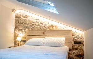 a bedroom with a white bed with a stone wall at Casa D'Mina in Redondela