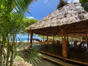 eine Hütte mit Stühlen und einer Hängematte am Strand in der Unterkunft Casa Yosi, Beach Front Piece of Heaven in San Juan del Sur