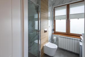 a bathroom with a toilet and a glass shower at Zakątek Apartments in Kraków