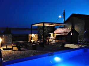 un patio con una mesa y un pabellón por la noche en STONE VILLA-MILAN Pool Sea View Lounge Room en Starigrad-Paklenica