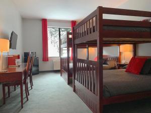 a bedroom with a bunk bed and a desk and a deskablish at Auberge Val Saint-Côme in Saint Come