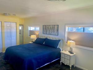 a bedroom with a blue bed with two lamps and a window at Greybull Motel in Greybull