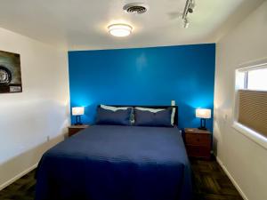 een blauwe slaapkamer met een bed en 2 lampen bij Greybull Motel in Greybull