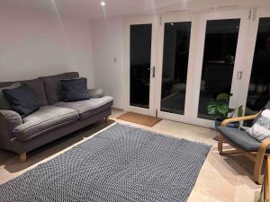 sala de estar con sofá, 2 sillas y alfombra en Littlewood Cabin en Hatherleigh