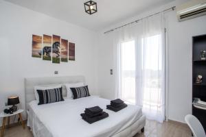 a white bedroom with a bed and a large window at Villa Tranquility in Psinthos
