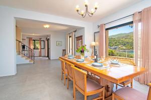 een eetkamer met een tafel en stoelen en een groot raam bij Villa Thalassia by Villa Plus in Kassiopi