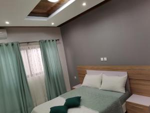 una camera da letto con letto e tende verdi di FOUR IN ONE RESIDENTIAL HOMES a Limbe