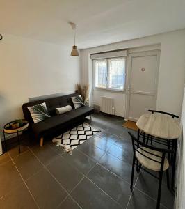 salon z czarną kanapą i stołem w obiekcie Le Central : Appartement cosy et calme w mieście Saint-Germain-de-Joux
