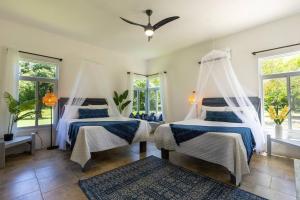 two beds in a room with windows at Ivy's Cove Beach Side Condo - Luxury Villa in Whitehouse