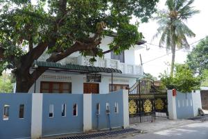 a white house with a tree in front of it at Nilo's Guest House in Batticaloa