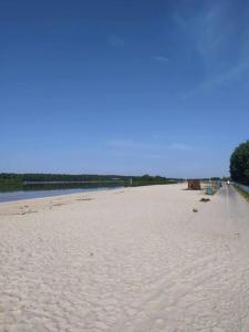 einen weißen Sandstrand mit blauem Himmel und Wasser in der Unterkunft "Chatki Nad Zalewem" Kluczbork in Ligota Zamecka