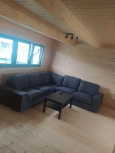 ein Wohnzimmer mit einem blauen Sofa und einem Tisch in der Unterkunft "Chatki Nad Zalewem" Kluczbork in Ligota Zamecka