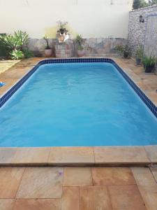 una gran piscina azul con un patio de ladrillo en Vila agradável e confortável com piscina en Pirenópolis