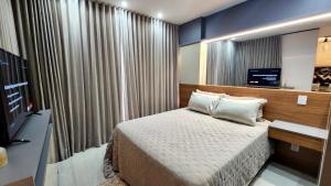 a small bedroom with a bed and a television at Estúdio Luxuoso no Vertigo com Smart TV na Cama in Campo Grande +7 photos