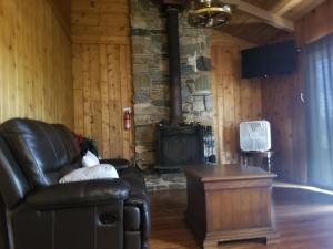 a living room with a leather chair and a stone fireplace at 3BR Panoramic Lake View, Sequoia Forest, Kern County in Wofford Heights