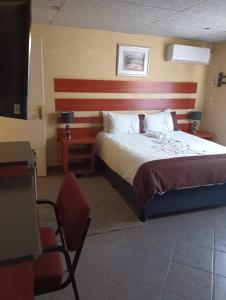 a hotel room with a bed and a chair at Prison View Guesthouse 1 in Klerksdorp