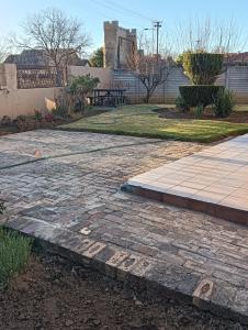 a stone walkway with a picnic table in a yard at Prison View Guesthouse 1 in Klerksdorp