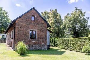 a brick house in a yard with a hedge at Chalupa Říkovice in Řikovice