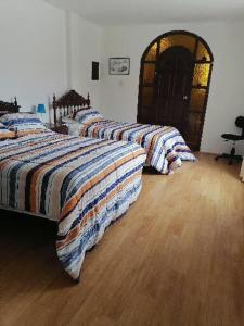 eine Reihe von 3 Betten in einem Zimmer mit Holzböden in der Unterkunft SAN PAOLY. in Trujillo