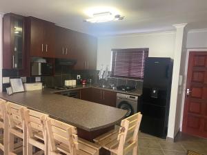 eine Küche mit einem schwarzen Kühlschrank und einem Tisch mit Stühlen in der Unterkunft Riekert's Self-Catering Apartment @Silver Sands in Swakopmund