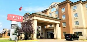 a hotel with a car parked in front of it at Merit Hotel & Suites in Fort McMurray