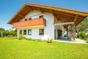 a house with a balcony and a lawn at Ferienwohnung Am Moosbach in Übersee