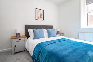a bedroom with a large bed with a blue blanket at Tobago St Apartment, Greenock in Greenock