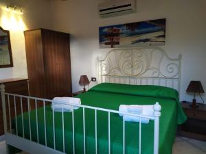 una camera da letto con un letto verde e asciugamani di Residence Villarcangelo a Marina di Camerota