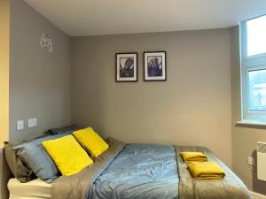 um quarto com uma cama com almofadas amarelas em HNFC Stays - Modern central studio with Gym, Parking & Home Cinema em Newcastle upon Tyne