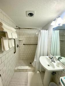 y baño blanco con lavabo y ducha. en Greybull Motel, en Greybull
