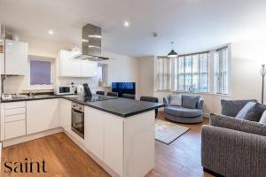 a kitchen and living room with white cabinets and a couch at 2BR Apartment in Central Beeston with Parking in Nottingham