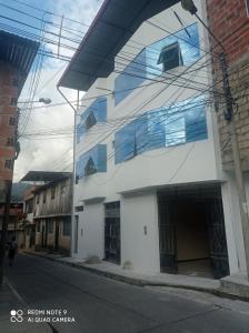 a white building with blue windows on a street at Casa Alojamiento Virreynal in San Ramón